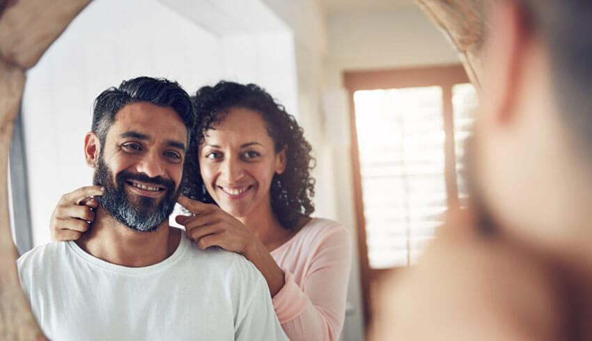 A man and woman smiling at their reflection in a mirror